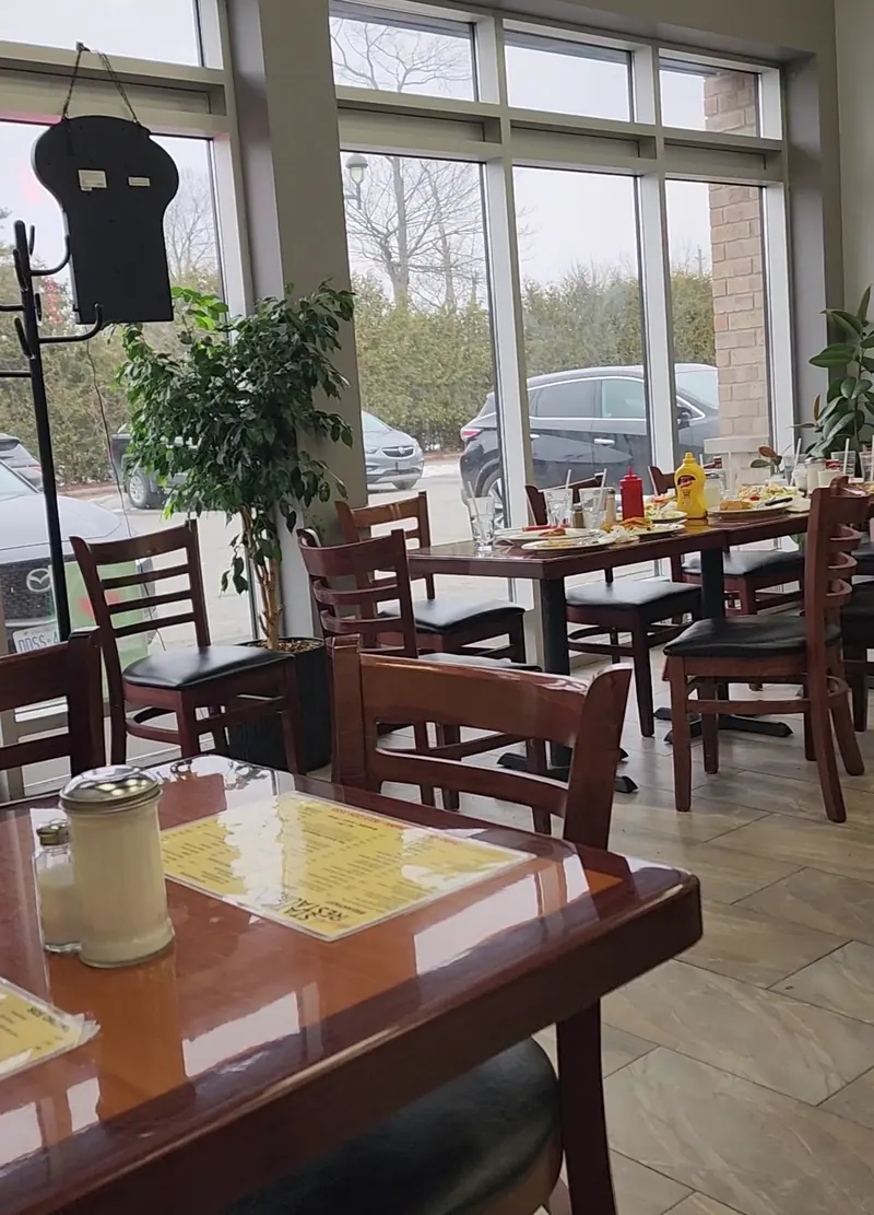 The dining room, with wooden tables, dark padded chairs and tall windows