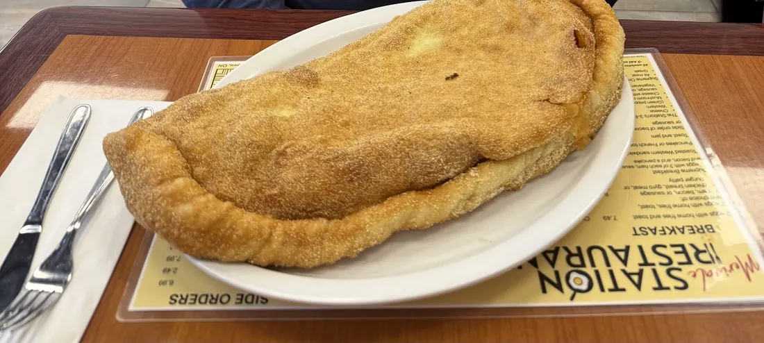 A very large golden panzerotti on a white plate